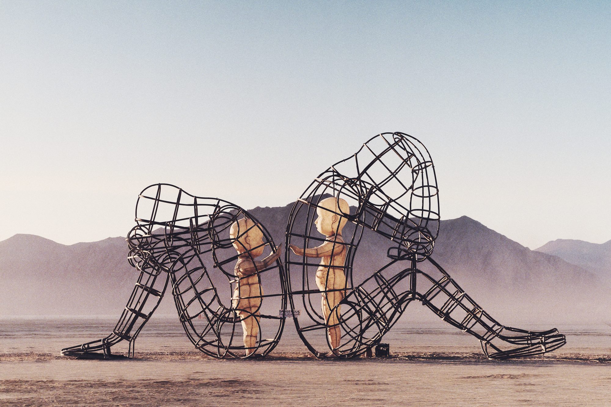 Het beeld Love van Alexander Milov op Burning Man 2015: twee volwassenen met de rug naar elkaar, de kinderen in hen reiken naar elkaar